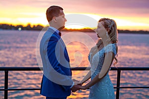 Young beautiful couple of newlyweds with bride and groom walk on the terrace by the ocean during a wedding ceremony in a wedding