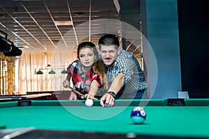 Young and beautiful couple playing billiard together