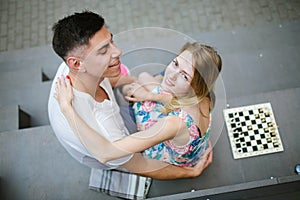 Young beautiful couple playing chess outdoors in city