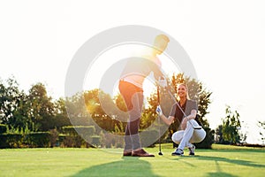 Young couple playing golf. Personal trainer giving lesson on golf course.