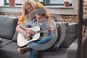 young beautiful couple playing guitar together at home