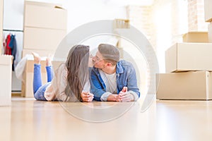 Young beautiful couple relaxing lying on the floor around cardboard boxes at home, smiling happy moving to a new house