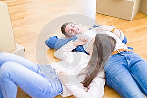 Young beautiful couple relaxing lying on the floor around cardboard boxes at home, smiling happy moving to a new house