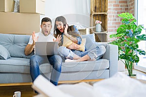 Young beautiful couple relaxing sitting on the sofa of new house using computer laptop very happy and excited, winner expression