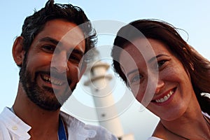 Young beautiful couple's portrait with Cap de Barberia's lighthouse on soft background, Formentera.