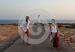 Young beautiful couple`s portrait with Cap de Barberia`s lighthouse on soft background, Formentera, Balearic Islands, Spain photo