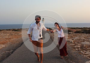 Young beautiful couple`s portrait with Cap de Barberia`s lighthouse on soft background, Formentera, Balearic Islands, Spain