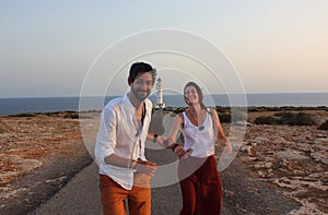 Young beautiful couple`s portrait with Cap de Barberia`s lighthouse on soft background, Formentera, Balearic Islands, Spain