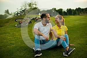 Young beautiful couple sitting on grass in the park.