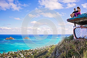 Young beautiful couple sitting on pillbox over looking Lanikai i