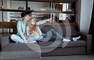 Young beautiful couple sitting on the sofa watching TV together