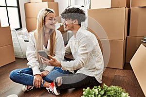 Young beautiful couple smiling happy using smartphone at new home
