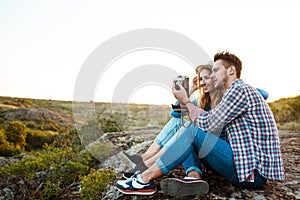 Young beautiful couple smiling, taking picture of canyon landscape.