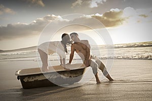 Young beautiful couple spending afternoon on beach with old bath tub