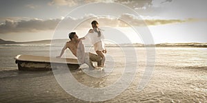 Young beautiful couple spending afternoon on beach with old bath tub