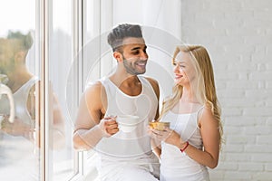 Young Beautiful Couple Stand Near Big Window, Drink Morning Coffee Cup, Happy Smile Hispanic Man And Woman