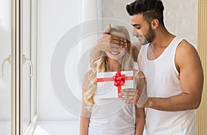 Young Beautiful Couple Stand Near Big Window, Hispanic Man Give Woman Surprise Present Envelope With Ribbon