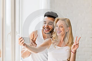 Young Beautiful Couple Stand Window, Taking Selfie Photo On Cell Smart Phone