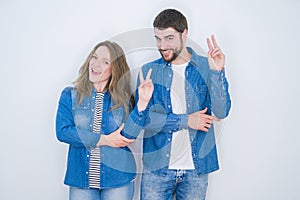 Young beautiful couple standing together over white isolated background smiling with happy face winking at the camera doing