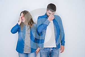 Young beautiful couple standing together over white isolated background tired rubbing nose and eyes feeling fatigue and headache