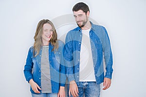 Young beautiful couple standing together over white isolated background winking looking at the camera with sexy expression,