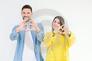 Young beautiful couple togheter over isolated background smiling in love showing heart symbol and shape with hands