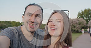 A young beautiful couple of tourists with braces make selfies in the park.