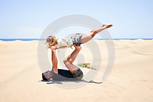 Young beautiful couple trainning acroyoga at the beach