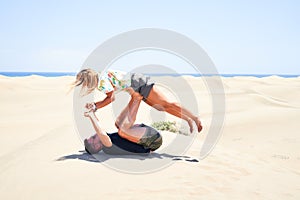 Young beautiful couple trainning acroyoga at the beach