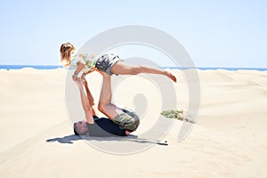 Young beautiful couple trainning acroyoga at the beach