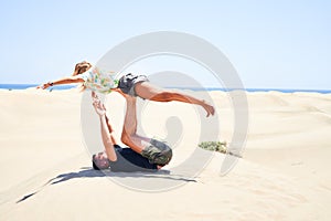 Young beautiful couple trainning acroyoga at the beach