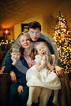 Young beautiful couple with two children posing in a chair in a Christmas interior