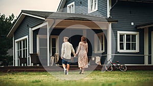 Young Beautiful Couple Walking Outdoors Towards the Country House, Holding Hands. Y