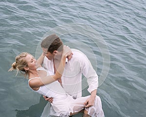 Young beautiful couple wearing white in body of water