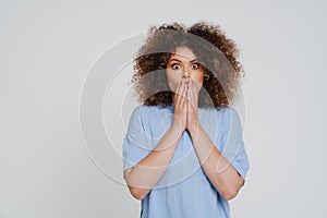 Young beautiful curly scared woman covering her mouth both hands