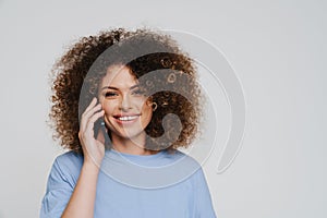 Young beautiful curly smiling woman talking phone looking at camera