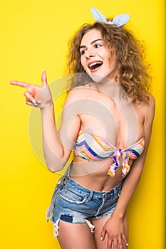 Young beautiful curly woman pointed on side with happy fency mo