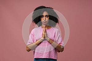 Young beautiful curly woman with puckered lips doing praying gesture