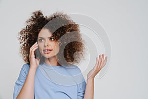 Young beautiful curly woman talking phone looking aside and gesturing