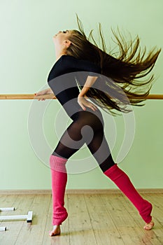 Young beautiful dancer posing in studio wit Ballet bar on tiptoe. Modern brunette.