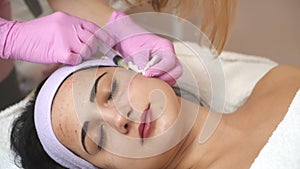 Young beautiful dark-haired woman gets rejuvenating facial injections. Work of the cosmetologist. Aesthetic cosmetology.