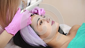 Young beautiful dark-haired woman gets rejuvenating facial injections. Work of the cosmetologist. Aesthetic cosmetology.
