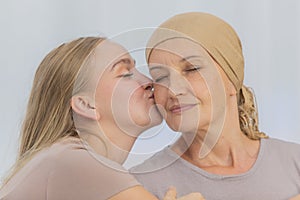 A young and beautiful daughter kiss her mother cancer patient and fortifies her to fight during the chemotherapy. Concept for love