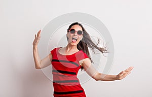 A young beautiful delighted woman with red sunglasses and t-shirt in a studio.