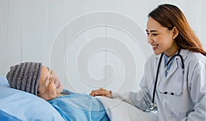 Young and beautiful doctor talking to older woman patient on the bed with the intimated manner to support and relax her from