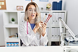 Young beautiful doctor woman holding diapason instrument clueless and confused expression