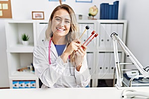 Young beautiful doctor woman holding diapason instrument smiling with a happy and cool smile on face