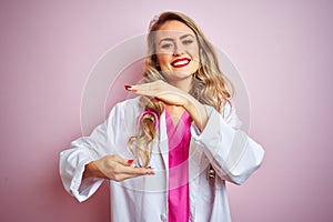 Young beautiful doctor woman using stethoscope over pink isolated background gesturing with hands showing big and large size sign,