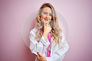 Young beautiful doctor woman using stethoscope over pink isolated background looking confident at the camera smiling with crossed