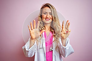 Young beautiful doctor woman using stethoscope over pink isolated background showing and pointing up with fingers number eight